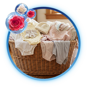 Canasta de mimbre con ropa delicada y de bebé organizada, decorada con burbujas de aroma a rosas Suavitel
