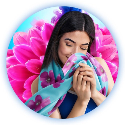 Mujer oliendo bufanda floral con los ojos cerrados, disfrutando el secreto de cómo hacer que la ropa huela rico con Suavitel.