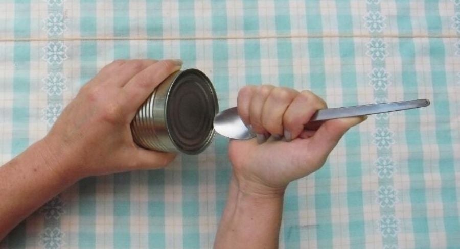 persona intentando abrir una lata con una cuchara