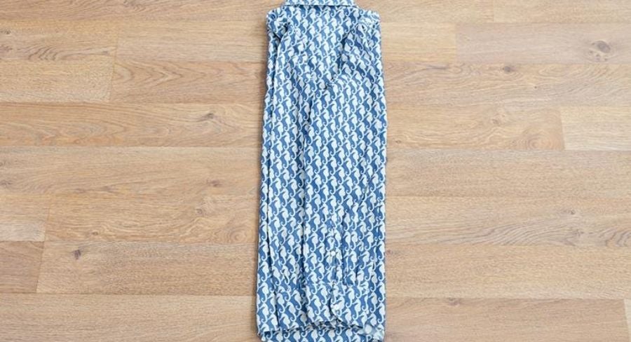 Proceso para doblar una camisa: Acomoda la manga a lo largo del doblez