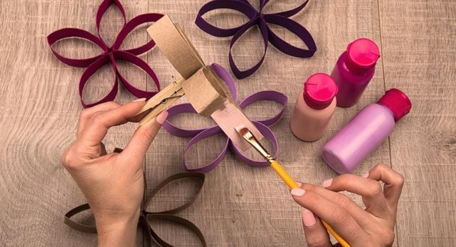 Pintando varias flores formadas con tubos de papel higiénico