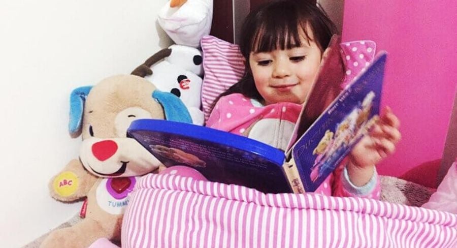niña leyendo en su cama sonriendo