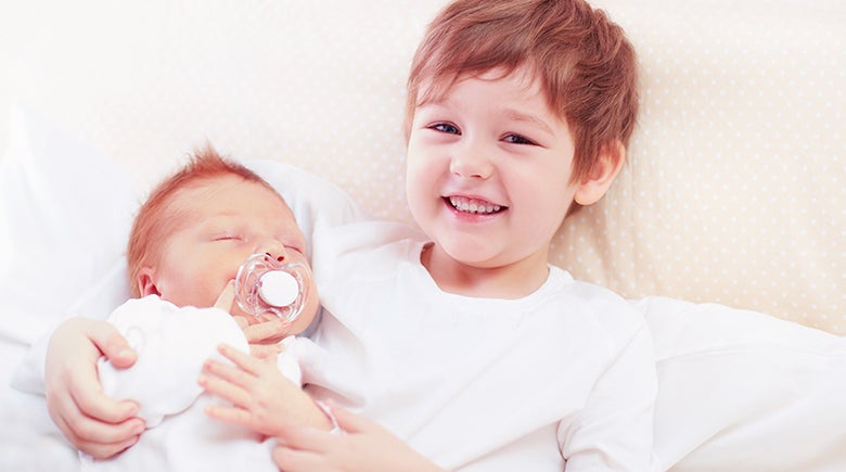 Consejos para cuando llega un hermano menor: Hermano mayor cuidando a bebé