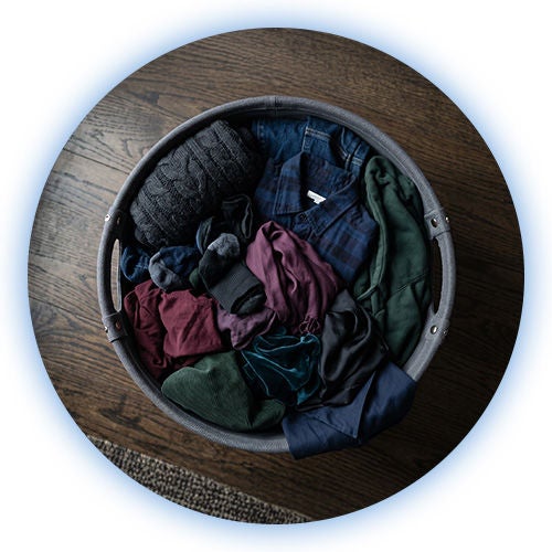 Cesta de mimbre con textiles oscuros agrupados para lavar ropa sin comprometer la intensidad del color.