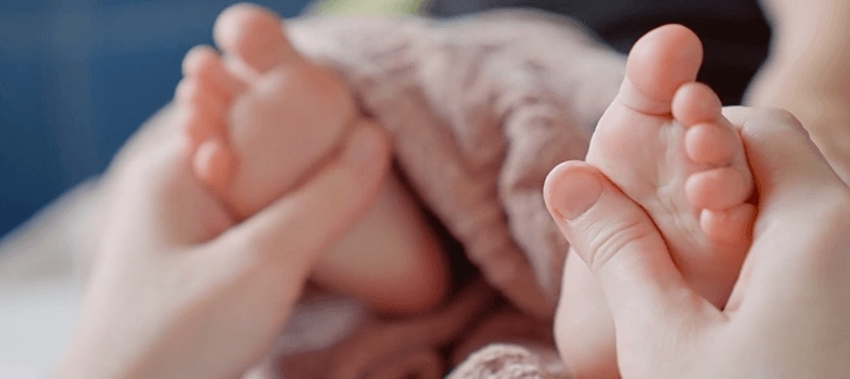 Mujer acariciando pies de bebe