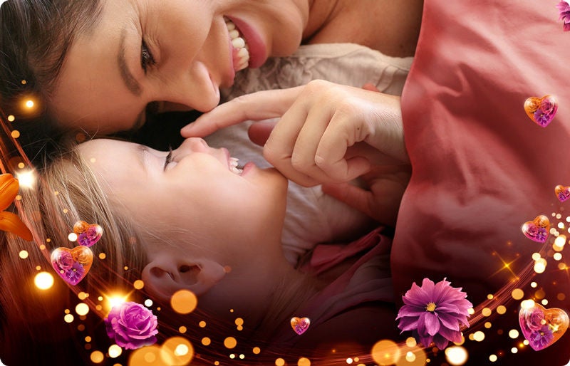 Mamá e hija sonriendo bajo las cobijas en un momento de amor y suavidad en el hogar.