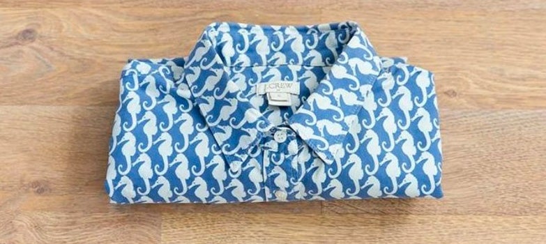 camisa azul de caballos marinos doblada de forma muy pequena