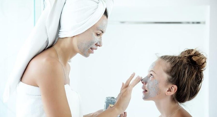 mamá aplicando crema en la cara de su hija