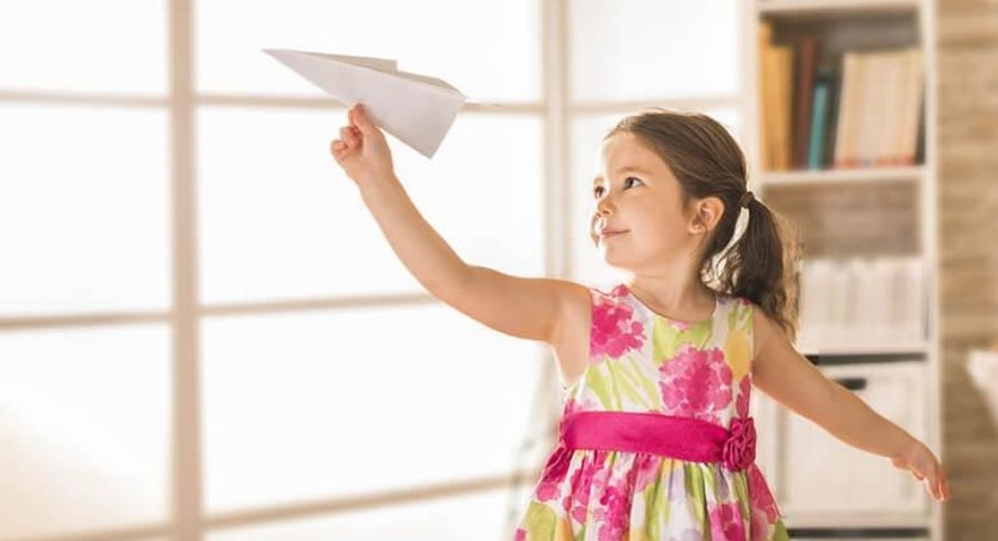 niña con avión de papel en la mano