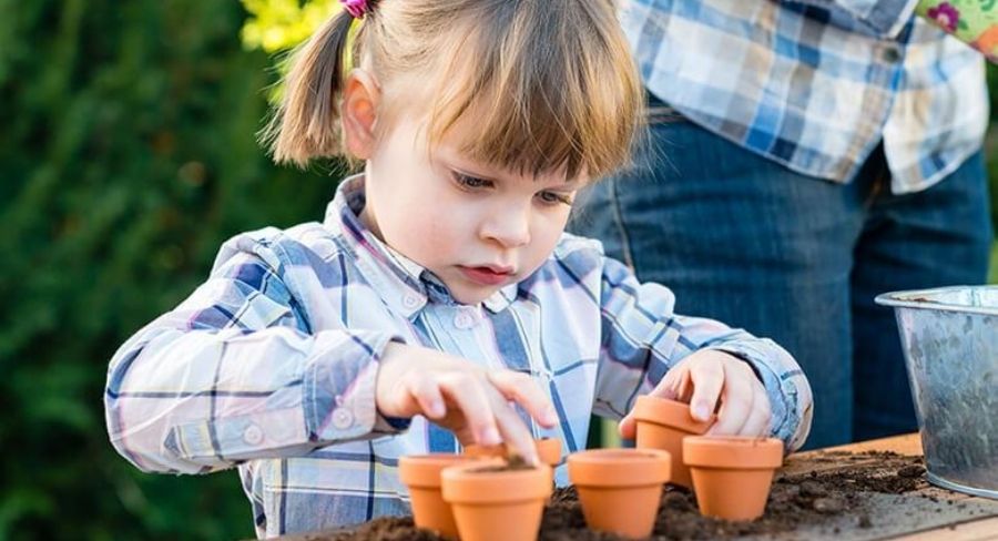 niña rubia sembrando una planta