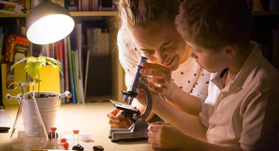 mamá e hijo mirando a través de un microscopio