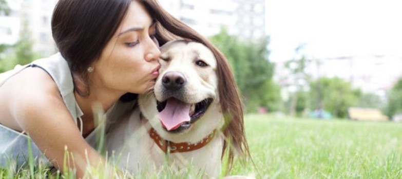 Mujer dando un beso a su perro mascota