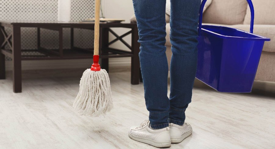 mujer con trapeador y cubeta lista para limpiar su casa