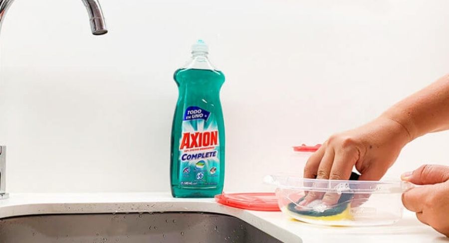 Persona lavando recipiente plastico con Axion poderoso arranca grasa
