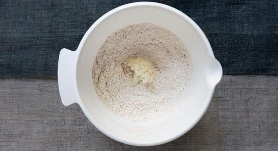Preparación de nuggets de coliflor: Empaniza los floretes con la mezcla de harina y especias. Asegúrate de cubrir completamente el florete de coliflor.