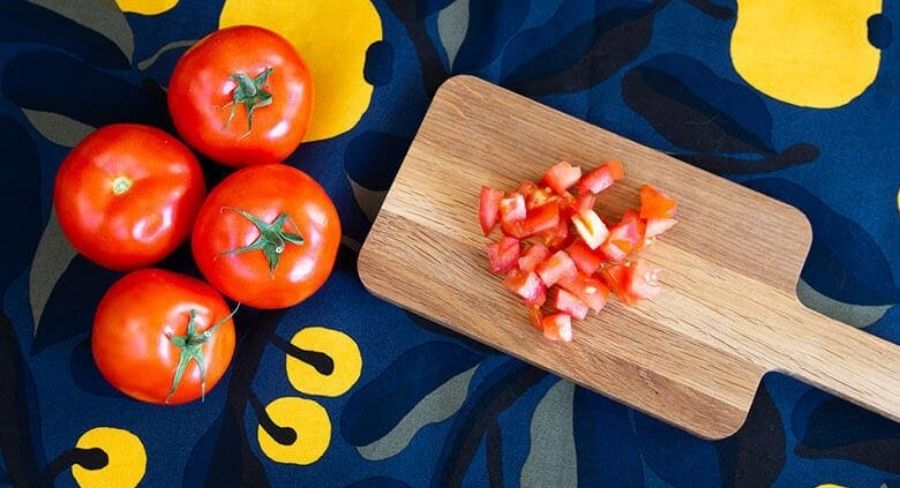 tomates frescos con una tabla con tomate picados en trozos 