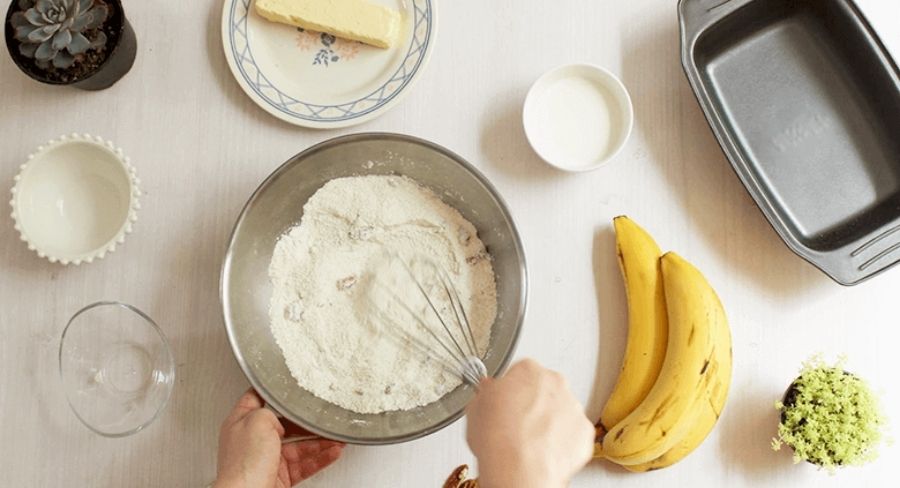 Budín de banana: En un recipiente ponemos los ingredientes secos; el azúcar, la canela en polvo, la harina, trozos de nuez, el polvo para hornear y mezclamos muy bien para que se integren todos los ingredientes.