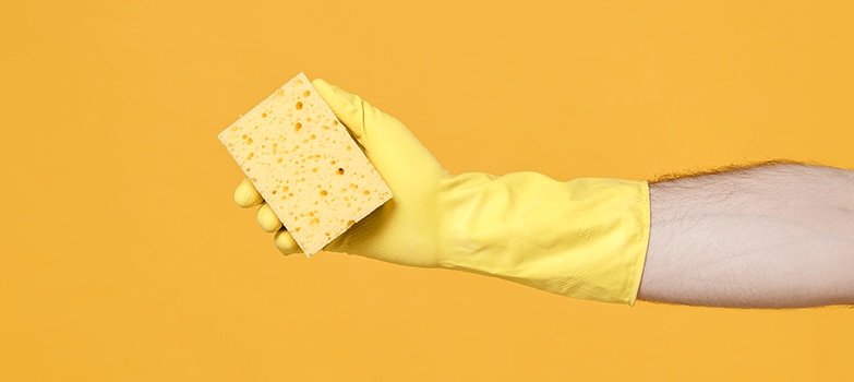 Manos usando guantes y tomando una esponja 
