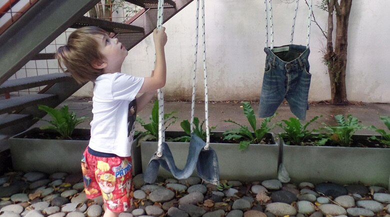 Columpio hecho con jeans viejos colgando de una rama de árbol