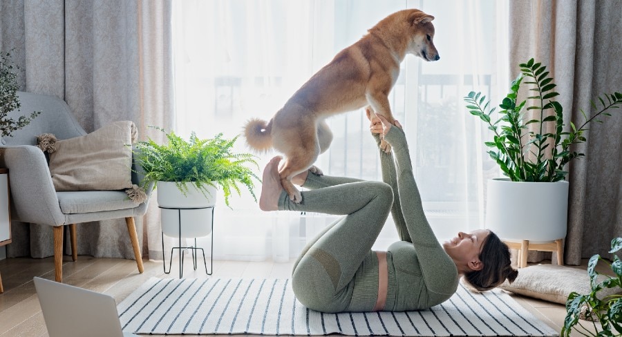 mujer recostada haciendo una pose de yoga junto con su perro